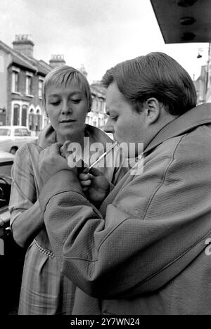 Actor Bill Wallis wearing a raincoat popularised by Premier Harold Wilson gets a light for his pipe from actress Myvanwyn Jenn . Bill and Myvanwyn will take the part of the Prime Minister and his wife in a play at the Theatre Royal in Stratford , London called Mrs Wilson's Diary . The theatre won a six month battle with the Lord Chamberlain's office to present the play . 18 September 1967 Stock Photo