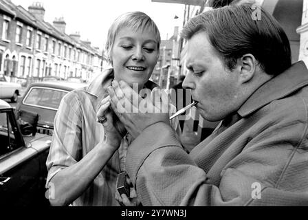 Actor Bill Wallis wearing a raincoat popularised by Premier Harold Wilson gets a light for his pipe from actress Myvanwyn Jenn . Bill and Myvanwyn will take the part of the Prime Minister and his wife in a play at the Theatre Royal in Stratford , London called Mrs Wilson's Diary . The theatre won a six month battle with the Lord Chamberlain's office to present the play . 18 September 1967 Stock Photo