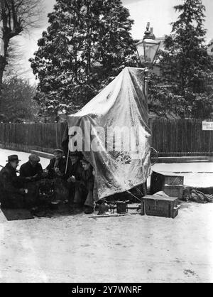 Workmen having lunch in the road in the snow. December 1938 Stock Photo