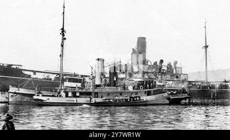 Chinese Piracy in the ' Sunning ' : Damaged by fire ; prisoners . Showing damage done amidships by the fire started by the Pirates : The British Steamer ' Sunning ' after having been towed back to Hong - Kong : with a tug and a fire - float standing by ( in the foreground ) .  18 December 1926 Stock Photo