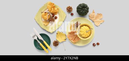 Autumn table setting with pumpkins, cones and dried leaves on light background Stock Photo
