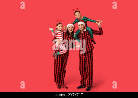 Happy family in Christmas pajamas on red background Stock Photo