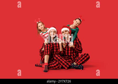 Happy family in Christmas pajamas on red background Stock Photo