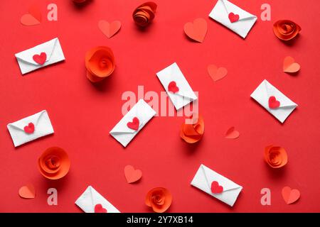 Envelopes with paper flowers and hearts on red background. Valentine's Day celebration Stock Photo
