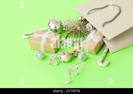 Paper shopping bag with Christmas gifts and beautiful decorations on green background Stock Photo