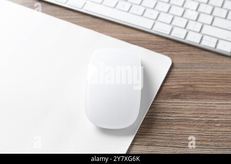 Computer mouse with mousepad and keyboard on wooden desk, closeup Stock Photo