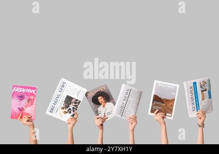 Female hands with different magazines and newspapers on grey background Stock Photo