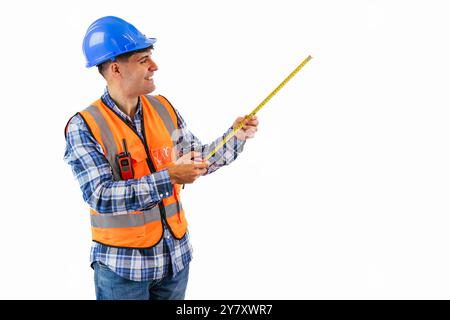 copyspace happy construction worker is confidently holding a measuring tape while dressed in an orange reflective vest and a safety helmet white backg Stock Photo