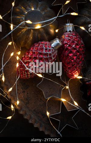 Old cookie cutters on tin with old Christmas tree decorations and fairy lights Stock Photo