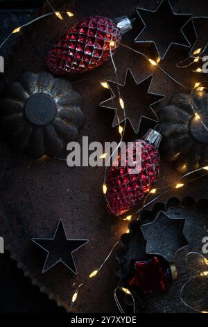 Old cookie cutters on tin with old Christmas tree decorations and fairy lights Stock Photo