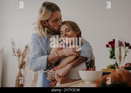 Young loving couple embracing and kissing while enjoying romantic dinner at home together Stock Photo