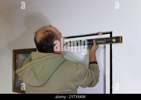 A worker's hands with  spirit level against frame of  the door. Home renovation, master installing door, using level tool for measure. An experienced Stock Photo