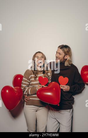Joyful loving couple holding heart shape Valentine cards on beige ...