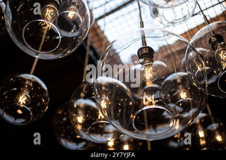 A view of a background of modern glass globe hanging light fixtures, seen in an interior facility. Stock Photo