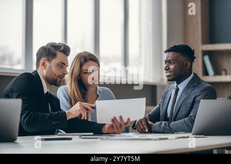 Concentrated young couple sitting at the office desk and examining papers while visiting financial advisor Stock Photo
