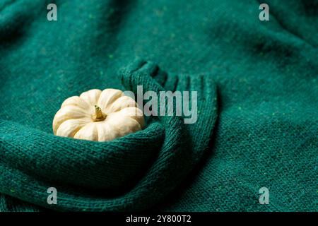 Orange pumpkin near a stack of knitted sweaters on a knitted blanket. Stock Photo