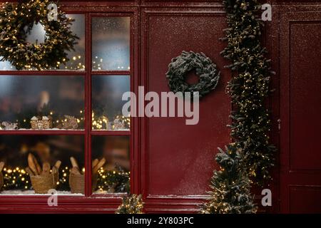 Christmas decor, a Christmas tree wreath on the wall, a brass candlestick with a burning candle Stock Photo