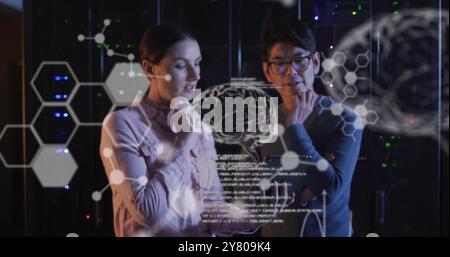 Image of data processing with brains over diverse colleagues using tablet in server room Stock Photo