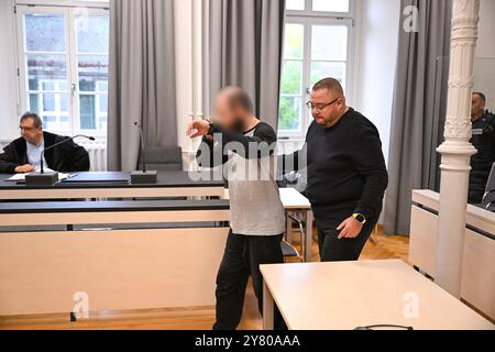 Ravensburg, Germany. 02nd Oct, 2024. A 34-year-old defendant enters the courtroom in handcuffs. The defendant is accused of attacking a four-year-old girl with a knife in a supermarket. The accused is led in by members of the judiciary. Credit: Felix Kästle/dpa - ATTENTION: Person(s) has/have been pixelated for legal reasons/dpa/Alamy Live News Stock Photo