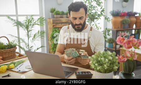 Middle-aged man counting united arab emirates dirhams in a vibrant flower shop Stock Photo