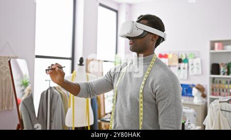 African american man wearing virtual reality headset in a modern tailoring atelier, with measuring tape around his neck. Stock Photo