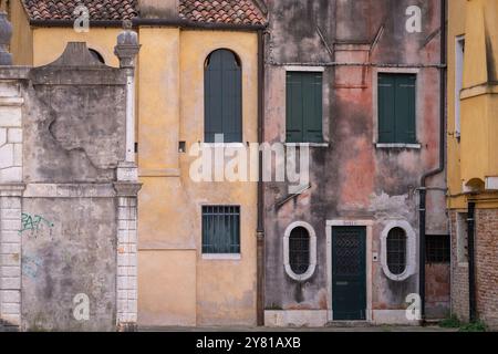 Colours of Venice. Background with plaster walls and windows with closed shutters. Venetian yellow, teal and dusty pink. Harmonious colours. Stock Photo