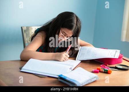 Goiania, Goias, Brazil – Setembro 20, 2024: A girl, child, wearing glasses, focused, doing homework. Studying at home. Stock Photo