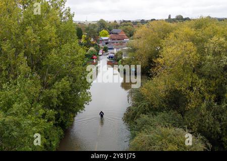 A man makes his way home along a flooded road in Offord Cluny, Cambridgeshire. Further showery spells are expected across England, but drier, more settled weather conditions are set to arrive in the coming days. Picture date: Wednesday October 2, 2024. Stock Photo