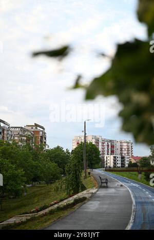 Urban bike path winding through greenery with buildings in the background Stock Photo