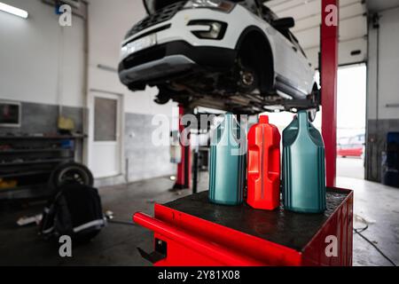 A garage scene showing american car on a lift with motor oil bottles in the foreground. Perfect for depicting automotive maintenance or repair setting Stock Photo