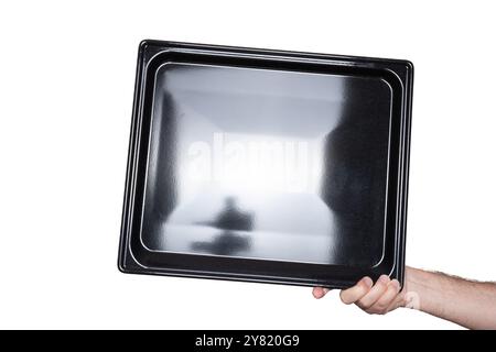 Empty, black, rectangular shallow baking tray. Held by hand by Caucasian male hand. Close up studio shot, isolated on white. Stock Photo