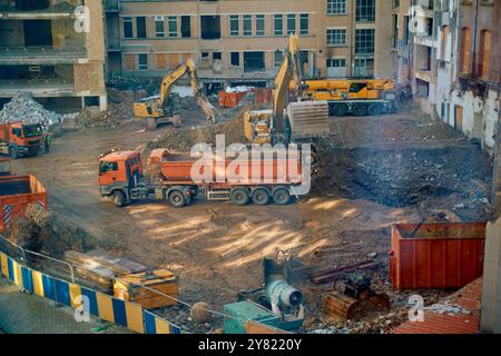 Construction site with excavators and trucks amidst demolition debris, viewed from above. Stock Photo