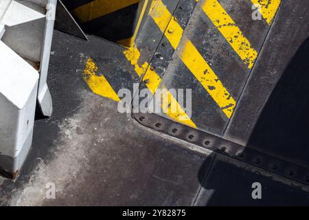 Black and yellow striped caution pattern painted over grungy steel panels. Abstract industrial background Stock Photo
