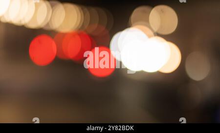 A blurred night scene featuring colorful bokeh lights in red, white, and orange hues. The lights create a dreamy and abstract effect, typical of night Stock Photo