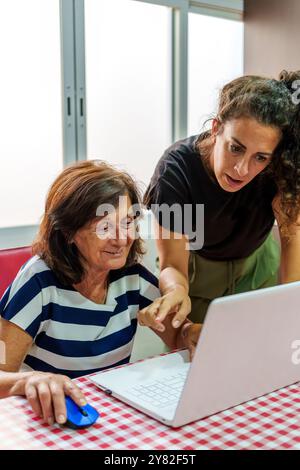 Middle-Aged Woman Teaching Senior Woman to Use a Laptop to Bridge the Digital Divide Stock Photo