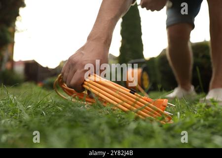 Man with extension cord on green grass outdoors, closeup Stock Photo