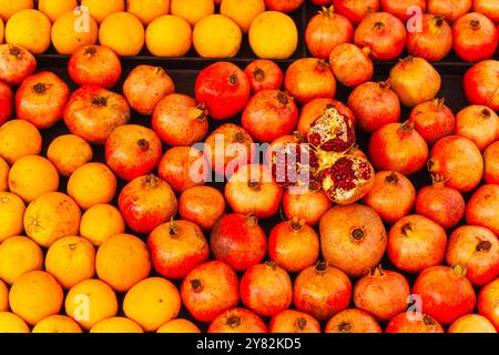 A vibrant assortment of oranges and pomegranates displayed on a table Stock Photo