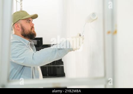 View through a stepladder on a man in construction gloves painting a wall  Stock Photo