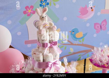 A baby shower with a pink and blue theme. A pink and white bunny is sitting on top of a stack of diapers Stock Photo