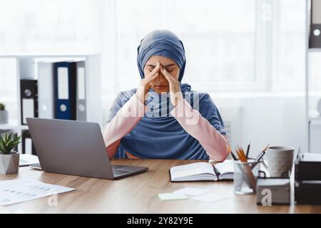 Portrait Of Exhausted Muslim Busineswoman In Hijab At Workplace In Office Stock Photo