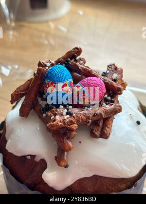 Festive easter cake is decorated with colorful chocolate eggs and crunchy pretzel sticks, creating a nest on top. Christian spring celebrations Stock Photo