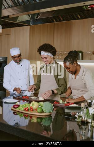Biracial cooking team working together in happy atmosphere in modern fully furnished kitchen Stock Photo