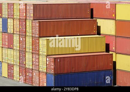 Yellow, orange, red and blue shipping cargo containers stacked in several layers at the port terminal, stack of containers in a harbor container termi Stock Photo