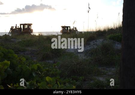 Silhouette at St. Pete Beach, FL towards Gulf of Mexico as heavy machines work on beach nourishment . View over sand and sea oats. Near sunset late Stock Photo