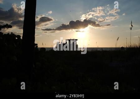 Silhouette at St. Pete Beach, FL towards Gulf of Mexico as heavy machines work on beach nourishment . View over sand and sea oats. Near sunset late Stock Photo