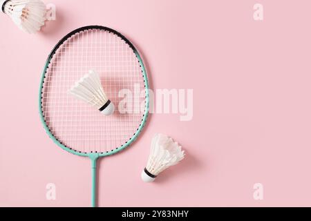 White feather badminton shuttlecocks and badminton racket on light pink background. View from above. Concept racket sport. Leisure games. Stock Photo