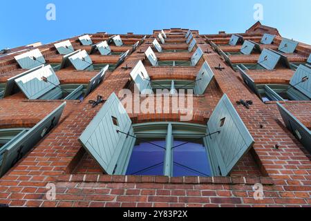 Historic red brick warehouse building with wooden shutters in the old town of Lubeck, Germany, view from below, blue sky, selected focus Stock Photo
