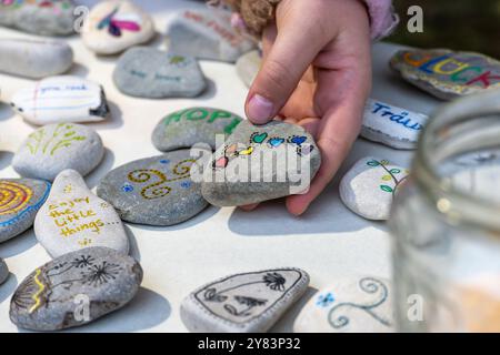 Collection of hand-painted pebbles with symbols, hand of a child holding one of them with the German with colorful hearts, creative giveaways to make Stock Photo