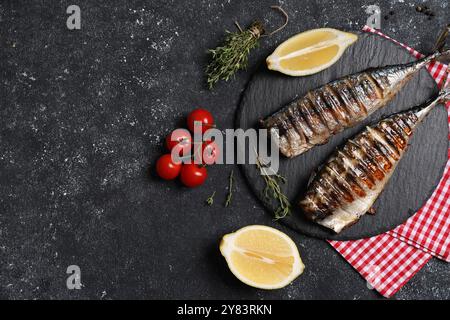 Delicious grilled mackerel, thyme, lemon and tomatoes on dark textured table, flat lay. Space for text Stock Photo