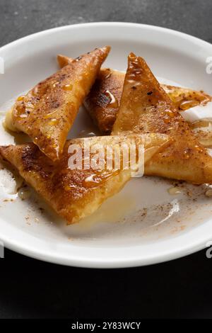 Mini cheese pies with myzithra, cretan honey and cinnamon on white plate. Stock Photo